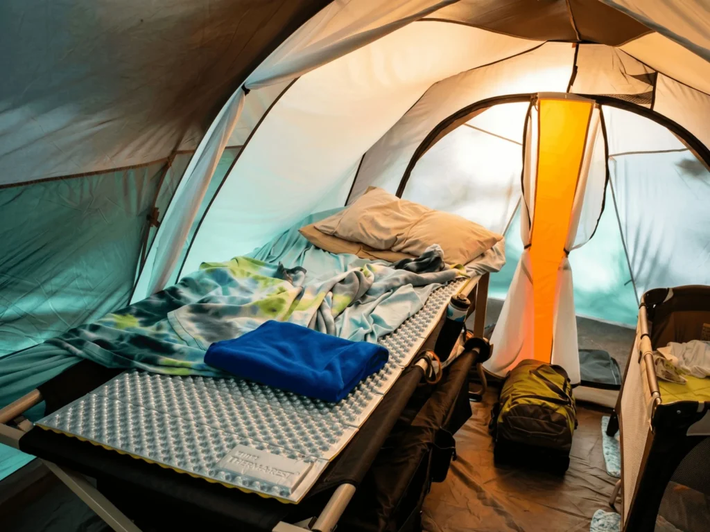 Foam sleeping pad layered on top of a camping cot with sleeping bag inside a tent
